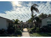 Charming pathway leads to the building entrance with lush tropical landscaping and unique architectural details at 2105 Pueblo Cir # V2, Sarasota, FL 34231