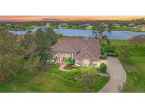 Stunning lakefront home with a lush lawn, mature trees, and a charming tile roof at 22642 Morning Glory Cir, Bradenton, FL 34202