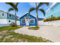 Charming blue home with tropical landscaping features a welcoming front door and ample parking space at 2408 Avenue B, Bradenton Beach, FL 34217