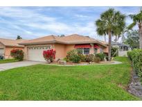 Charming home boasts a well-manicured lawn, mature landscaping, and a cheerful peach exterior at 4302 Turnberry Ct, Bradenton, FL 34210