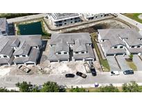 New construction shows modern townhomes with gray roofing near a pond in a developing community at 5628 Summit Point Cir # 103, Bradenton, FL 34210