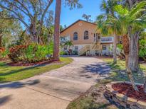 Charming two-story home with arched windows, brick driveway, lush landscaping and beautiful mature trees at 7717 27Th W Ave, Bradenton, FL 34209