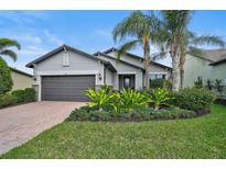 Charming one-story home with a brick driveway, well-manicured lawn, and attractive landscaping at 11050 Sandhill Preserve Dr, Sarasota, FL 34238
