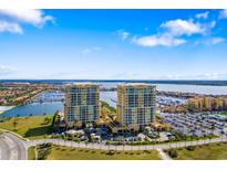Stunning aerial view of two luxury condo buildings overlooking a marina with waterfront views and parking at 130 Riviera Dunes Way # 1201, Palmetto, FL 34221