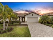 Beautiful single-story home with lush landscaping, paver driveway and two car garage under a colorful sunset sky at 17234 Blue Ridge Pl, Bradenton, FL 34211