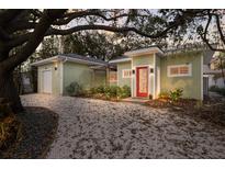 Charming single-story home with a landscaped yard, gravel driveway, and a vibrant red front door at 3521 Almeria Ave, Sarasota, FL 34239