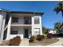 Two-story condo building featuring a front door, balcony, and lush landscaping against a blue sky at 4440 47Th W Ave # 204, Bradenton, FL 34210