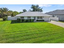 Charming single-story home featuring a well-maintained lawn, manicured shrubs, and a classic white exterior at 6320 Tilly St, Englewood, FL 34224