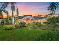 Inviting single-story home featuring a manicured lawn, lush tropical landscaping and a tile roof at sunset at 6617 Nautical Dr, Lakewood Ranch, FL 34202
