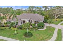 Beautiful single-story home featuring a lush lawn, tropical landscaping, tile roof, and paver driveway at 6617 Nautical Dr, Lakewood Ranch, FL 34202