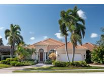 Charming home featuring lush tropical landscaping, a tile roof, and a two-car garage, creating great curb appeal at 7141 Whitemarsh Cir, Lakewood Ranch, FL 34202