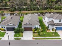 This aerial view shows well-manicured lawns and landscaping near a tranquil pond at 8619 Firefly Pl, Parrish, FL 34219