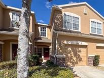 Inviting townhome featuring a one-car garage, a red front door, and beautiful stone accents at 11805 Castine St, New Port Richey, FL 34654