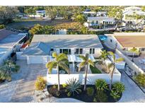 Beautifully landscaped home with a pristine white exterior, palm trees, and lush green lawn at 309 Avenida Milano, Sarasota, FL 34242