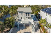 Two-story home with elevated deck, staircase, and covered parking surrounded by lush tropical landscaping at 462 Island Cir, Sarasota, FL 34242
