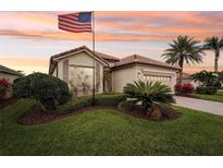 Charming single-story home with tile roof, an American flag, lush landscaping, and a two-car garage at 5105 Pine Shadow Ln, North Port, FL 34287