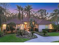 Charming single-story home featuring lush landscaping, a tile roof, and a welcoming walkway to the front door at 5416 Ashley Pkwy, Sarasota, FL 34241