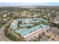 Scenic aerial view of a condo complex with a swimming pool and lush landscaping near the water at 5665 Midnight Pass Rd # 410, Sarasota, FL 34242