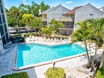 Aerial view of a community pool surrounded by lush landscaping and lounging area at 6157 Midnight Pass Rd # E42, Sarasota, FL 34242