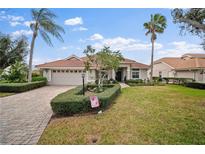 Charming single-story home with a manicured lawn, terracotta roof, and palm trees on a sunny day at 6955 Stetson Street Cir, Sarasota, FL 34243