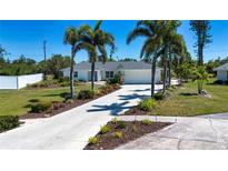 Charming single-story home featuring a well-manicured lawn, palm trees, and a long driveway at 2466 Breakwater Cir, Sarasota, FL 34231