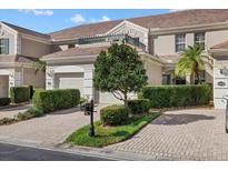 Beautiful exterior of townhome featuring a brick driveway, manicured landscaping, and neutral color palette at 7416 Botanica Pkwy # 103, Sarasota, FL 34238