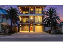 Charming three-story home with dual balconies, a brick driveway, and well-manicured palm trees at 108 Magnolia Ave, Anna Maria, FL 34216