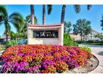 Fiesta Harbor entrance sign with colorful flowers, tropical foliage, and palm trees under a sunny blue sky at 1250 N Portofino Dr # 408Mar, Sarasota, FL 34242