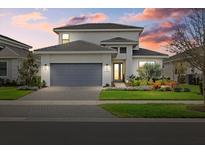 Beautiful two-story home with manicured landscaping, paver driveway, gray roof, and a gray garage door at 17814 Cresswind Ter, Bradenton, FL 34211