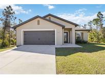 Charming single-story home with a two-car garage, well-manicured lawn, and inviting front entrance at 2721 Burri Ter, North Port, FL 34288