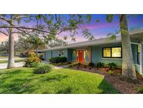 Charming home featuring an inviting red door, well-manicured lawn, and lush landscaping at 316 Scott Ave, Sarasota, FL 34243