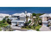 Coastal home featuring a white roof, three-car garage, and lush landscaping with direct access to the beach at 3540 Mistletoe Ln, Longboat Key, FL 34228