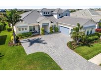 Elegant home featuring a paver driveway, lush landscaping, and a neutral color palette at 7928 Redonda Loop, Bradenton, FL 34202