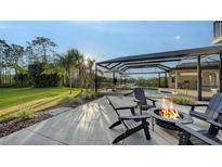 Relaxing backyard featuring a fire pit, screened pool, lake view, and lush landscaping at 9818 Old Hyde Park Pl, Bradenton, FL 34202
