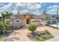 Elegant exterior featuring a paver driveway, lush landscaping, and a tile roof at 10494 Atenia St, Port Charlotte, FL 33981