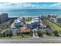 Expansive aerial view of beachside condos with private beach access, tennis courts, and lush landscaping at 1465 Gulf Of Mexico Dr # 104, Longboat Key, FL 34228