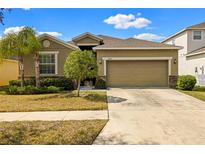 Charming single-story home with a two car garage, a well maintained lawn, and beautiful Florida landscaping at 16612 Myrtle Sand Dr, Wimauma, FL 33598