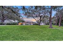 Charming single-story home featuring a metal roof, mature trees, and a lush green lawn at 4045 Lisbon Pl, Sarasota, FL 34231
