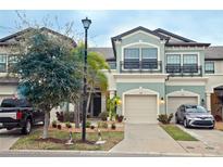 Charming townhome showcasing a two-car garage, light green exterior paint, and meticulously landscaped front yard at 5118 78Th St E Cir, Bradenton, FL 34203
