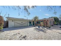 Charming brick and siding home featuring a large, paved driveway and a well-manicured front yard at 5525 Shadow Lawn Dr, Sarasota, FL 34242