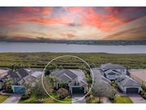 Stunning lakefront property with lush landscaping and beautiful architectural design under a colorful sunset sky at 5608 Tidewater Preserve Blvd, Bradenton, FL 34208