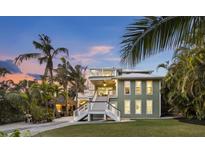 Charming two-story home with a rooftop deck, set amongst lush tropical landscaping and manicured lawn at 581 Broadway St, Longboat Key, FL 34228