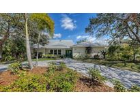Charming single-story home with a lush front yard, a paved driveway, and a metal roof at 614 Tropical Cir, Sarasota, FL 34242
