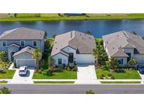 Aerial view of a home with a well-manicured lawn, landscaping, palm trees, and water view in a residential neighborhood at 6378 Grandview Hill Ct, Bradenton, FL 34203