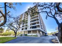 Stunning condo building exterior featuring multiple balconies and beautiful landscaping against a blue sky at 6415 Midnight Pass Rd # 904, Sarasota, FL 34242