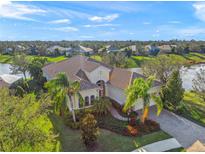 An impressive single-story home with a tile roof, lush landscaping, and picturesque lake views from an elevated perspective at 7108 Callander Cv, Lakewood Ranch, FL 34202