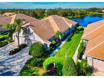 Inviting home with a well-manicured lawn, lush landscaping, and a serene lake in the backyard at 8310 Tartan Fields Cir, Lakewood Ranch, FL 34202