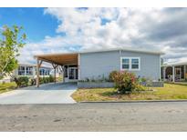 Charming single-story home features a light blue exterior, manicured landscaping, and a covered carport at 970 Jolanda Cir, Venice, FL 34285