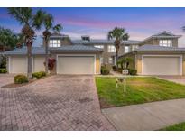 Charming townhomes featuring brick driveways, lush landscaping, and attached garages for convenient parking at 10600 Lemon Creek Loop # 102, Englewood, FL 34224