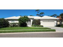 Charming single-story home with a well-manicured lawn, a two-car garage, and a pristine white tile roof at 629 Sawgrass Bridge Rd, Venice, FL 34292